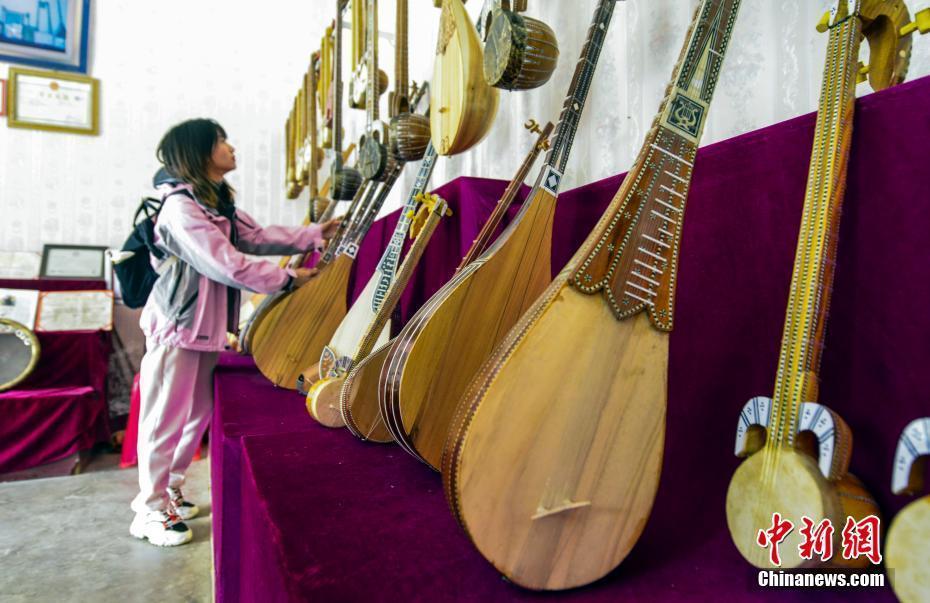 图为在新疆疏附县吐万克吾库沙克村,游客被制作精美的民族乐器所